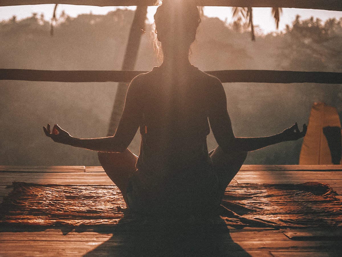 Personne en méditation au lever du soleil, illustrant le mieux-être